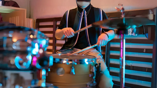 Masked drummer playing indoor kit with lights